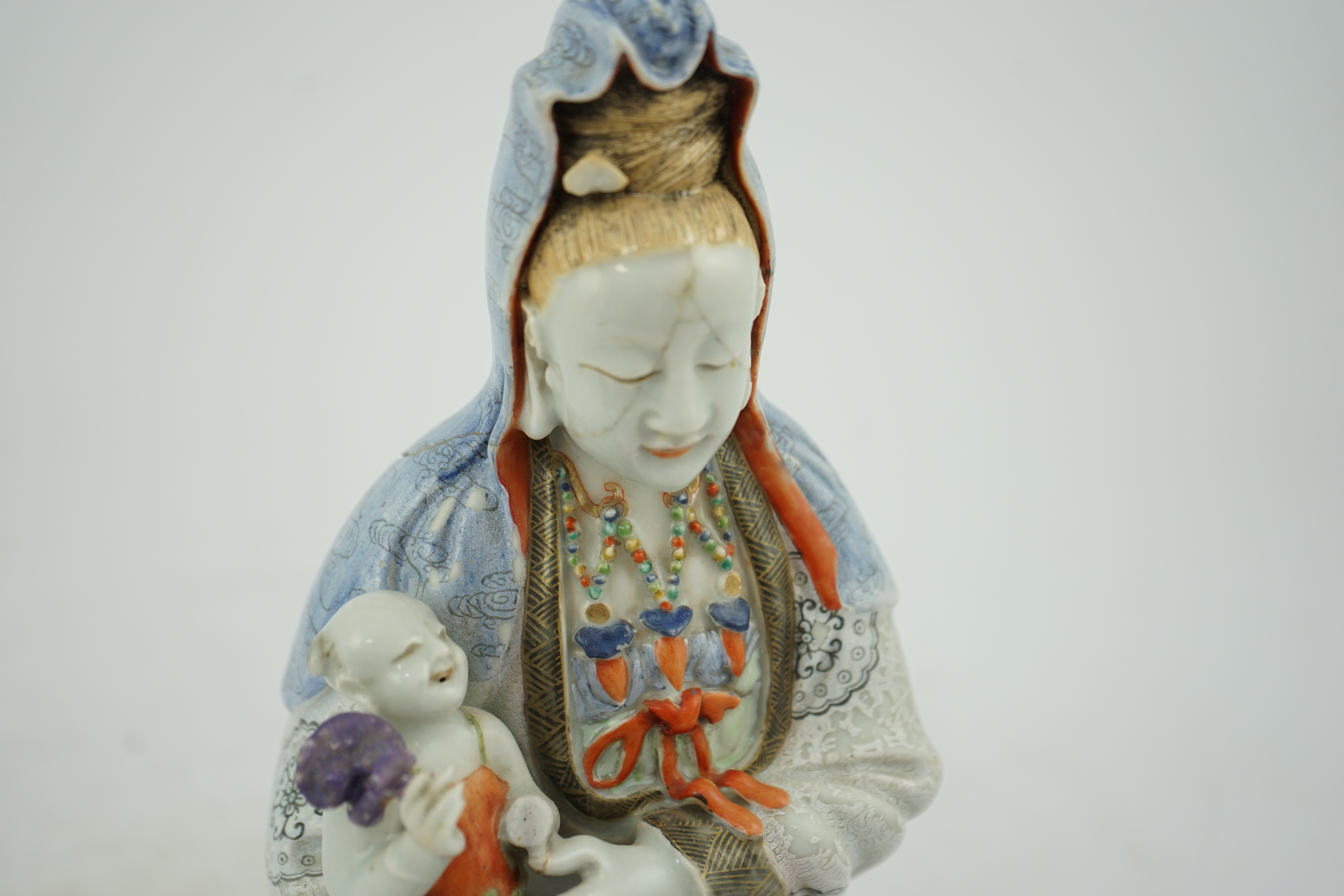 A Chinese enamelled porcelain group of Guanyin holding a child, Qianlong period